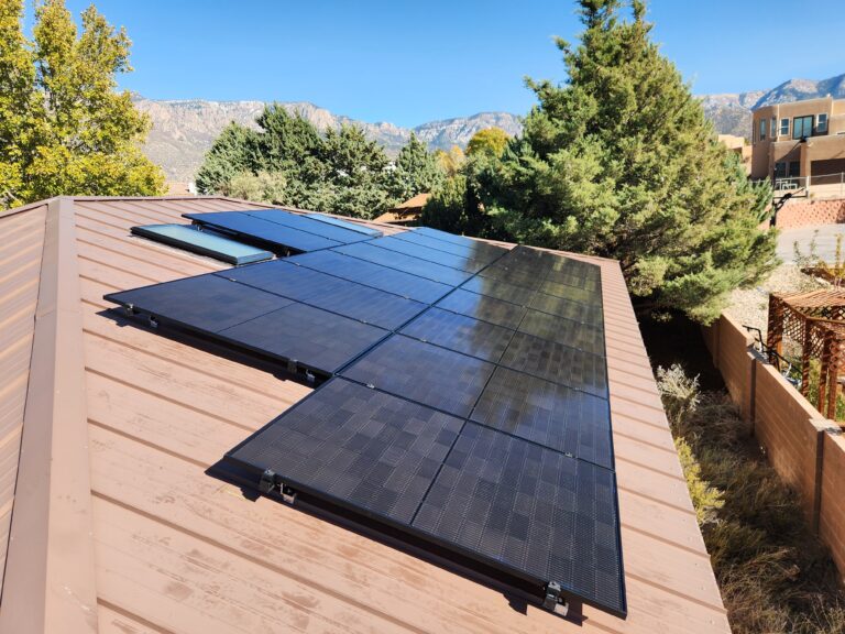 black solar panels on a metal roof with mountains in the background